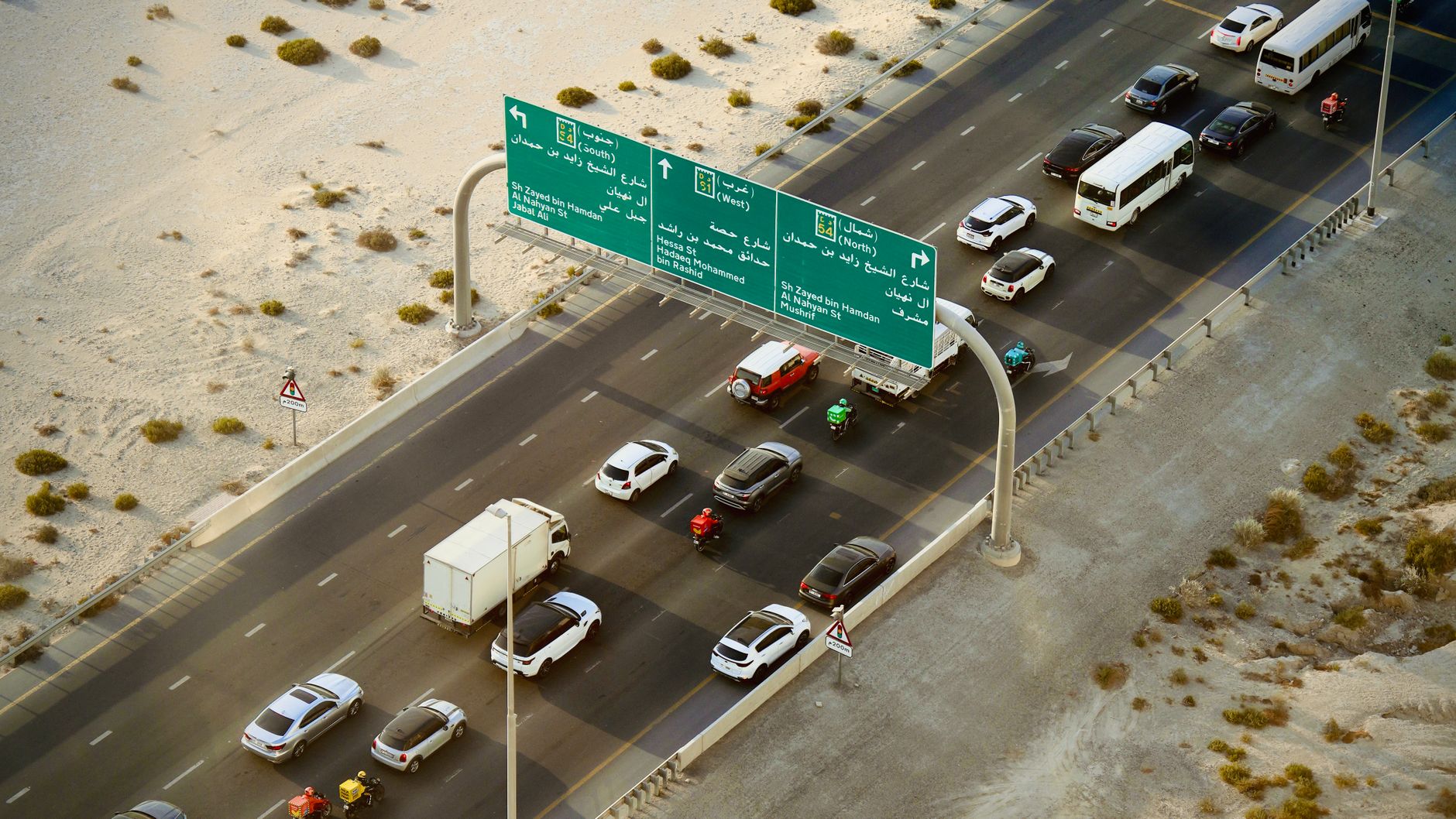 Traffic moving along a Dubai highway past overhead road signs