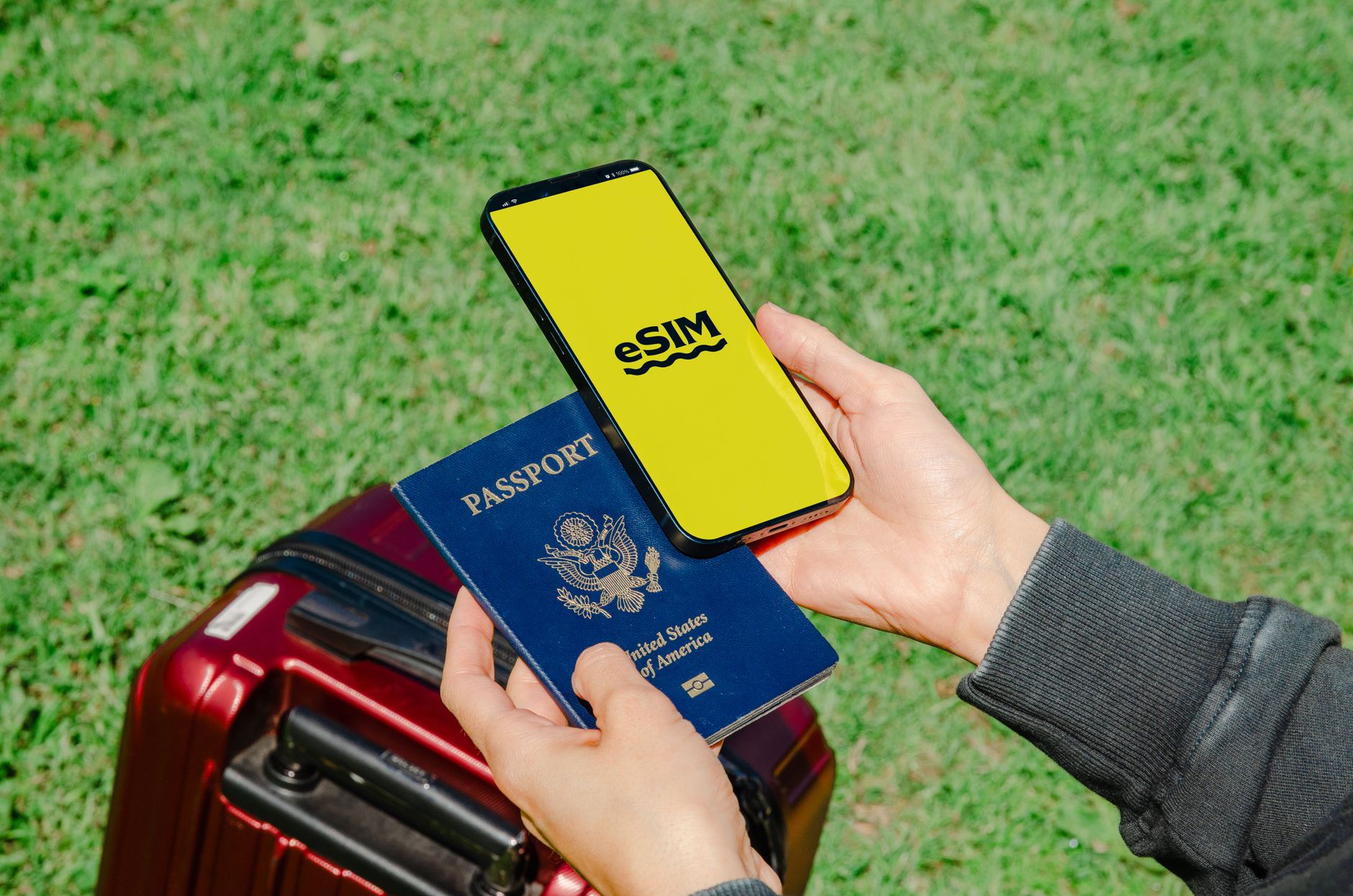 A smartphone showing an eSIM screen, held next to a passport and luggage